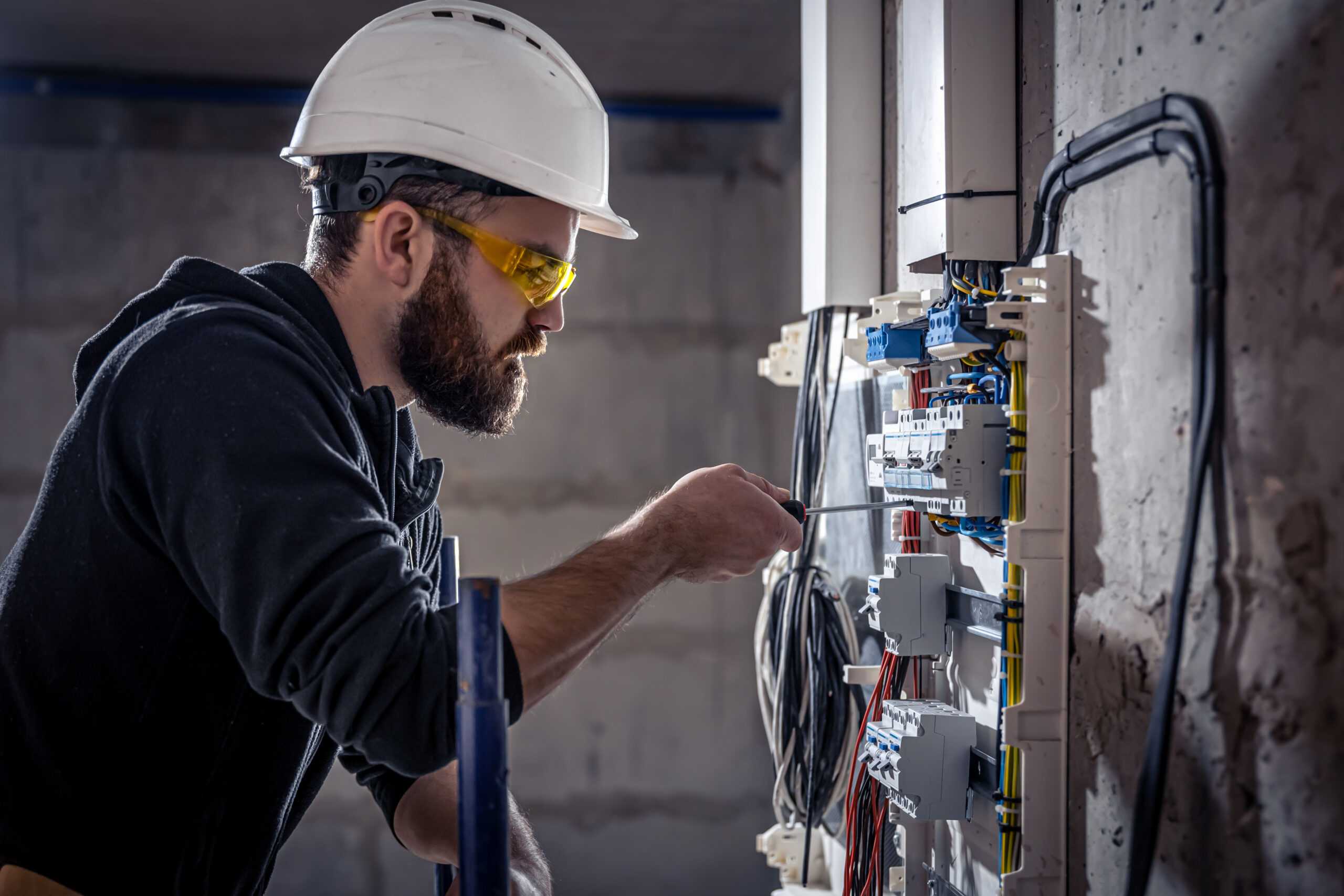 male electrician works switchboard with electrical connecting cable 1 scaled.jpg